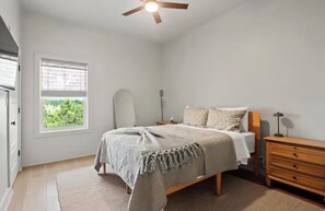 A bedroom with a bed, bedside table, lamp, and a window with a view. - 3-bedroom house in Henderson Point (Pass Christian)