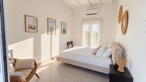A bedroom with a bed, a chair, and a nightstand. - Cas Seida - Private Pool Villa Pure Aruba (Oranjestad)