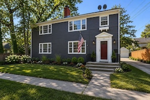 A two-story house with a dark siding exterior, white trim, and a red front door.
