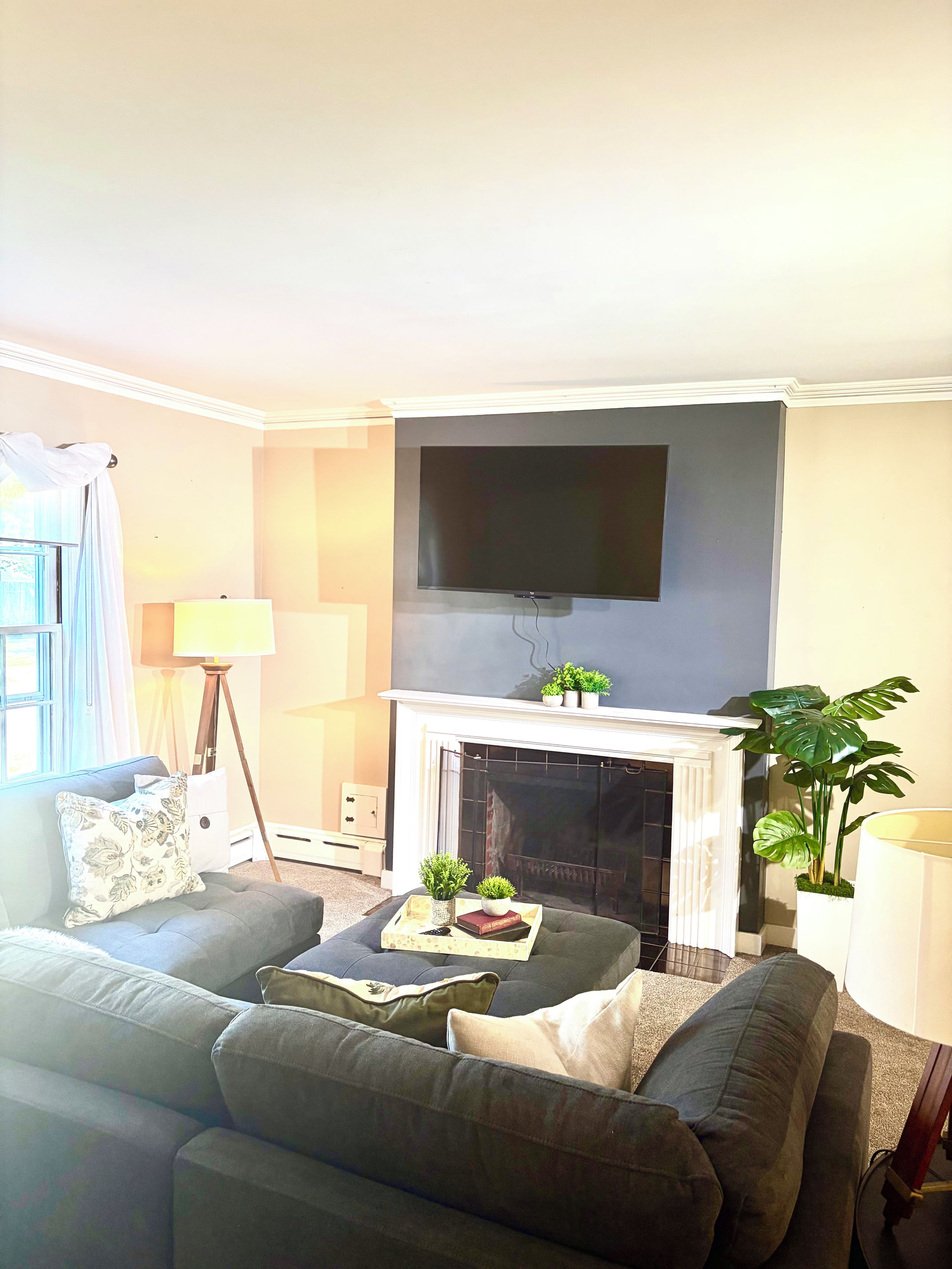 A living room with a sofa, a flat-screen TV mounted above a fireplace, and a lamp.