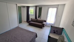Quarto com cama, sofá, janela com cortinas e uma caminha para animais de estimação.