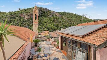Un pati amb paviment de rajoles, mobles d'exterior i un edifici amb una torre campanar.