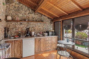 Una cuina rústica amb parets de pedra, armaris de fusta i un terra de rajoles.