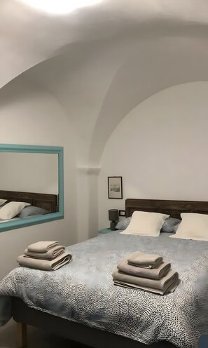 Ein Schlafzimmer mit einem Bett, einem Nachttisch, einer Lampe und einem gerahmten Bild an der Wand.