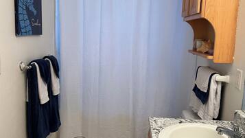 A bathroom with a shower curtain, a toilet, a sink, and a towel rack.