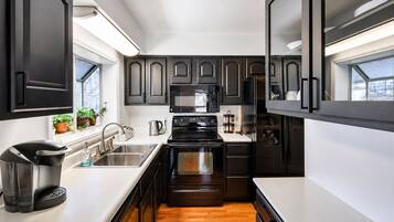 A modern kitchen with dark cabinetry, stainless steel appliances, and a white countertop.