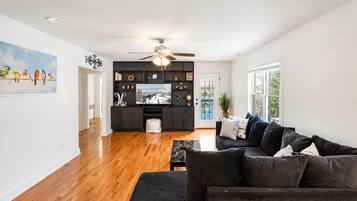 A modern living room with a black sofa, a coffee table, and a television on a black entertainment unit.