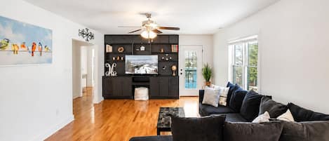 A modern living room with a black sofa, a coffee table, and a television on a black entertainment unit.