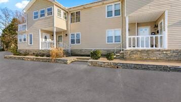 A two-story building with a stone foundation, a front porch, and a garage.