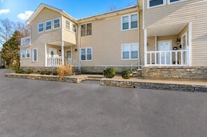 A two-story building with a stone foundation, a front porch, and a garage.