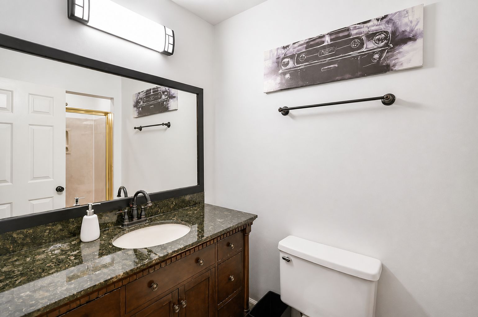 A bathroom with a marble sink, a toilet, a mirror, and a towel rack.