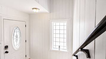 A white door with a glass panel, a window with a grid pattern, and a black metal handrail.