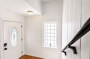 A white door with a glass panel, a window with a grid pattern, and a black metal handrail.