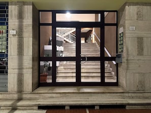 A set of stairs leading to an upper floor, enclosed by a glass door with a metal handle.