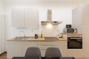 Une cuisine moderne équipée d’un évier, d’une cuisinière, d’un four à micro-ondes et d’un four traditionnel.