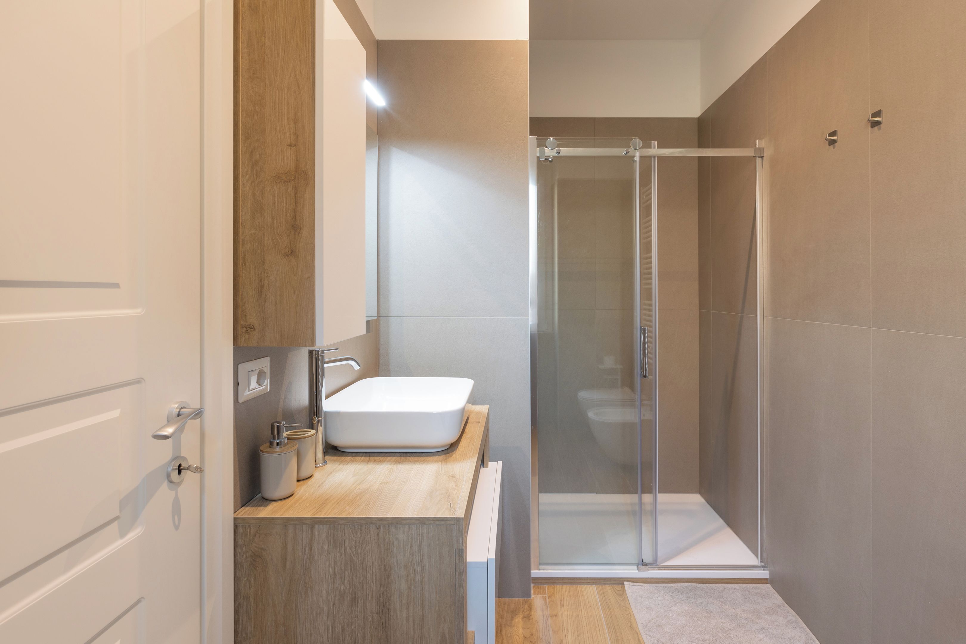 A modern bathroom with a shower, a sink, and a toilet.