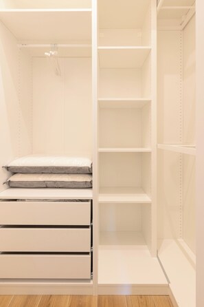 A walk-in closet with open shelves, a hanging rod, and a padded bench. - Gaffurio Apartment J (Milano)