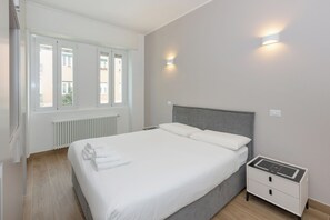 A bedroom with a bed, a bedside table, a radiator, and a window. - Gaffurio Apartment J (Milano)