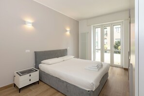 Ein Schlafzimmer mit Bett, Nachttisch und Blick ins Freie durch eine Glastür.