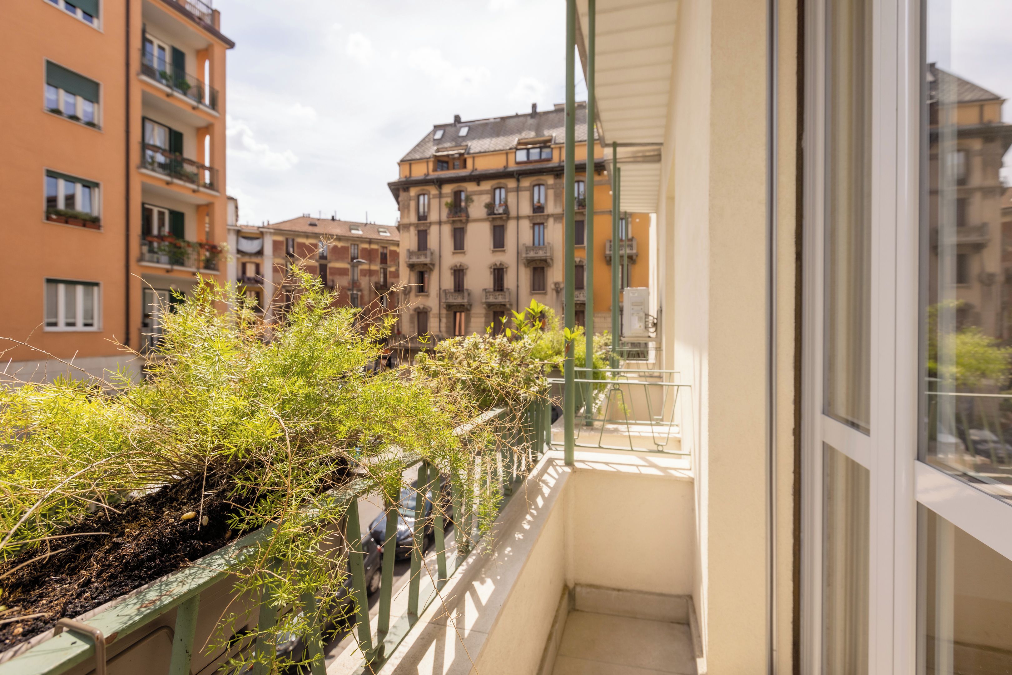 A balcony with a view of multi-story buildings, a metal railing, and a clear sky.