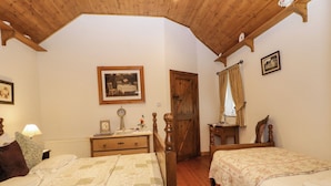 A bedroom with two beds, wooden headboard, a dresser, a clock, and a framed picture on the wall. - Teresa's Cottage (Bruckless)