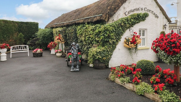 A traditional building with ivy-covered walls and a thatched roof, labeled 'Cora's Cottage.' - Teresa's Cottage (Bruckless)