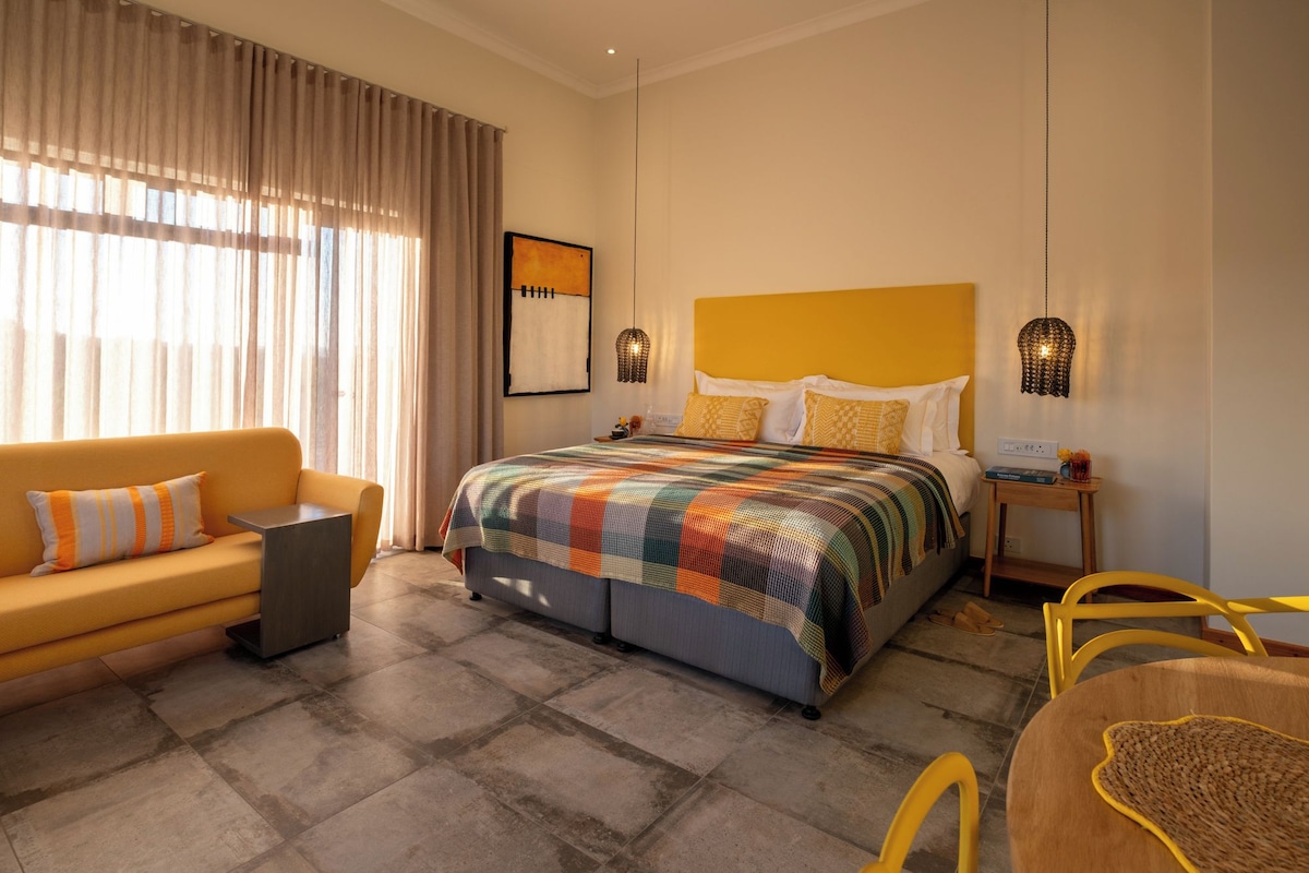 Una habitación de hotel con una cama, un sofá, una mesita y una silla.