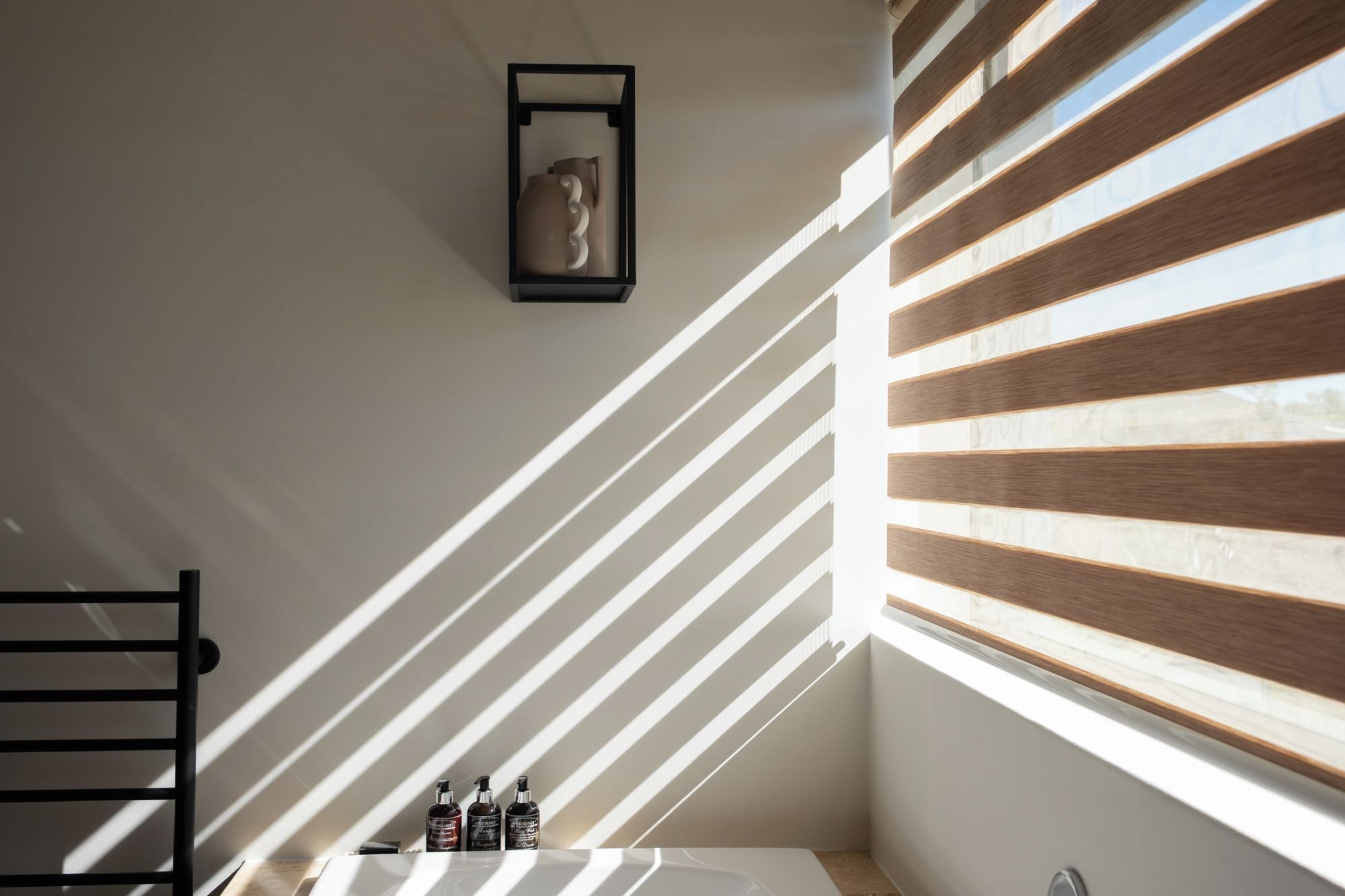 A bathroom with a bathtub, a towel rack, and a window with blinds.