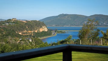 A coastal landscape with a prominent hill, a road curving along the coast, and a body of water.