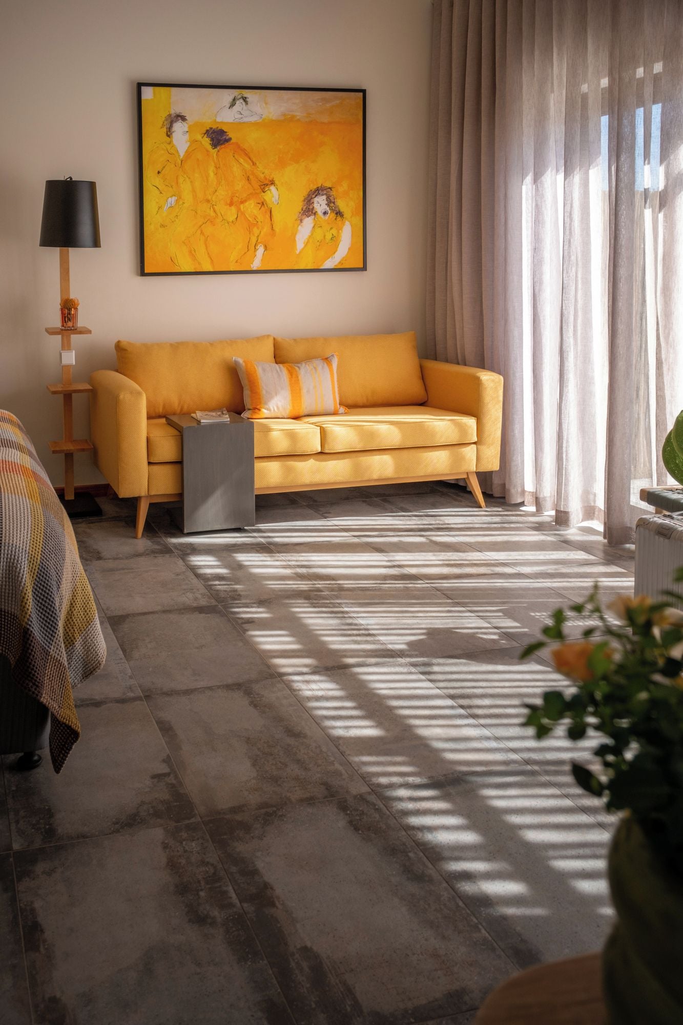 Una sala de estar con sofá, un cuadro, una lámpara y una ventana con cortinas.