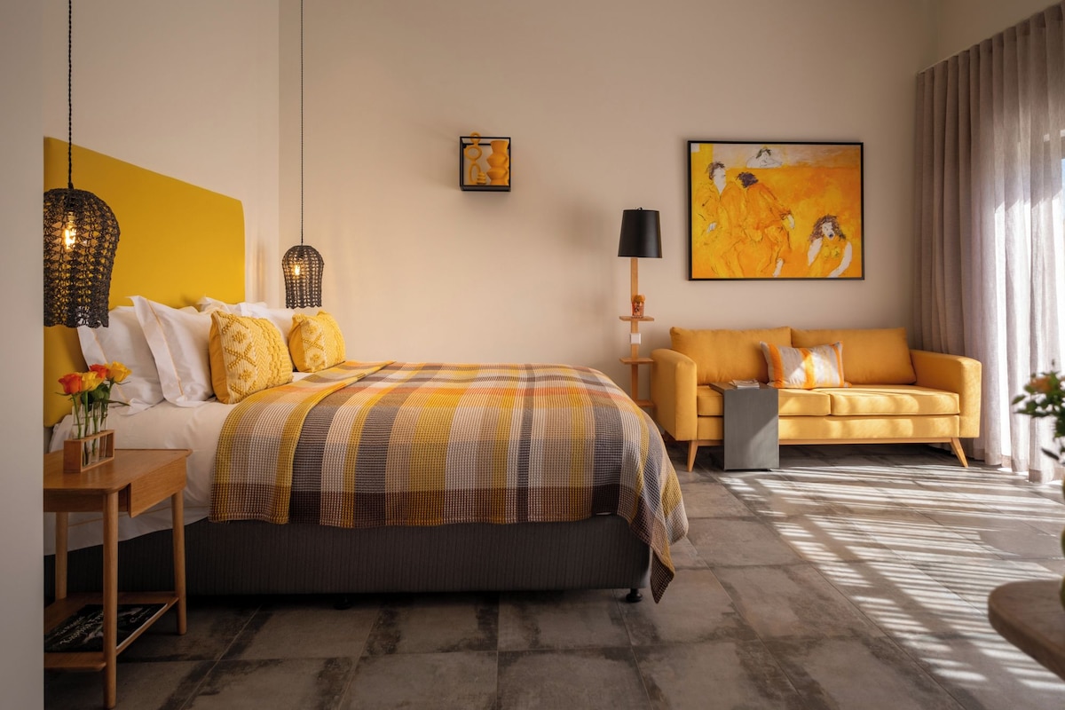 Una habitación de hotel con cama, sofá, lámpara y obras de arte en las paredes.