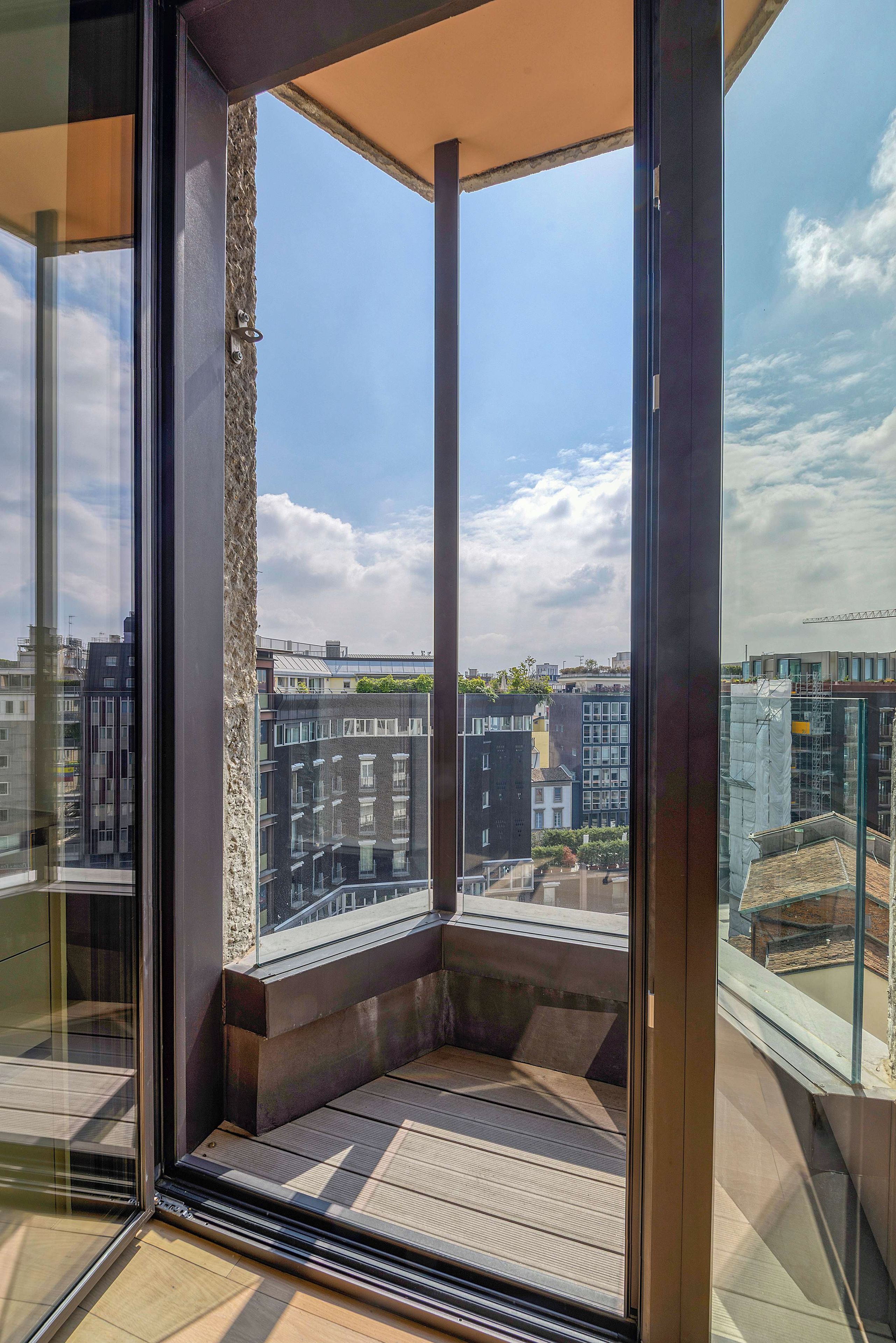 Un balcone moderno con vista aperta sulla città, tra cui edifici e una gru edile.