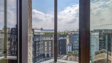 Un balcone moderno con vista aperta sulla città, tra cui edifici e una gru edile.