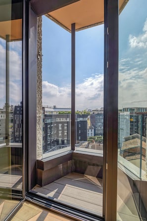 Un balcone moderno con vista aperta sulla città, tra cui edifici e una gru edile.