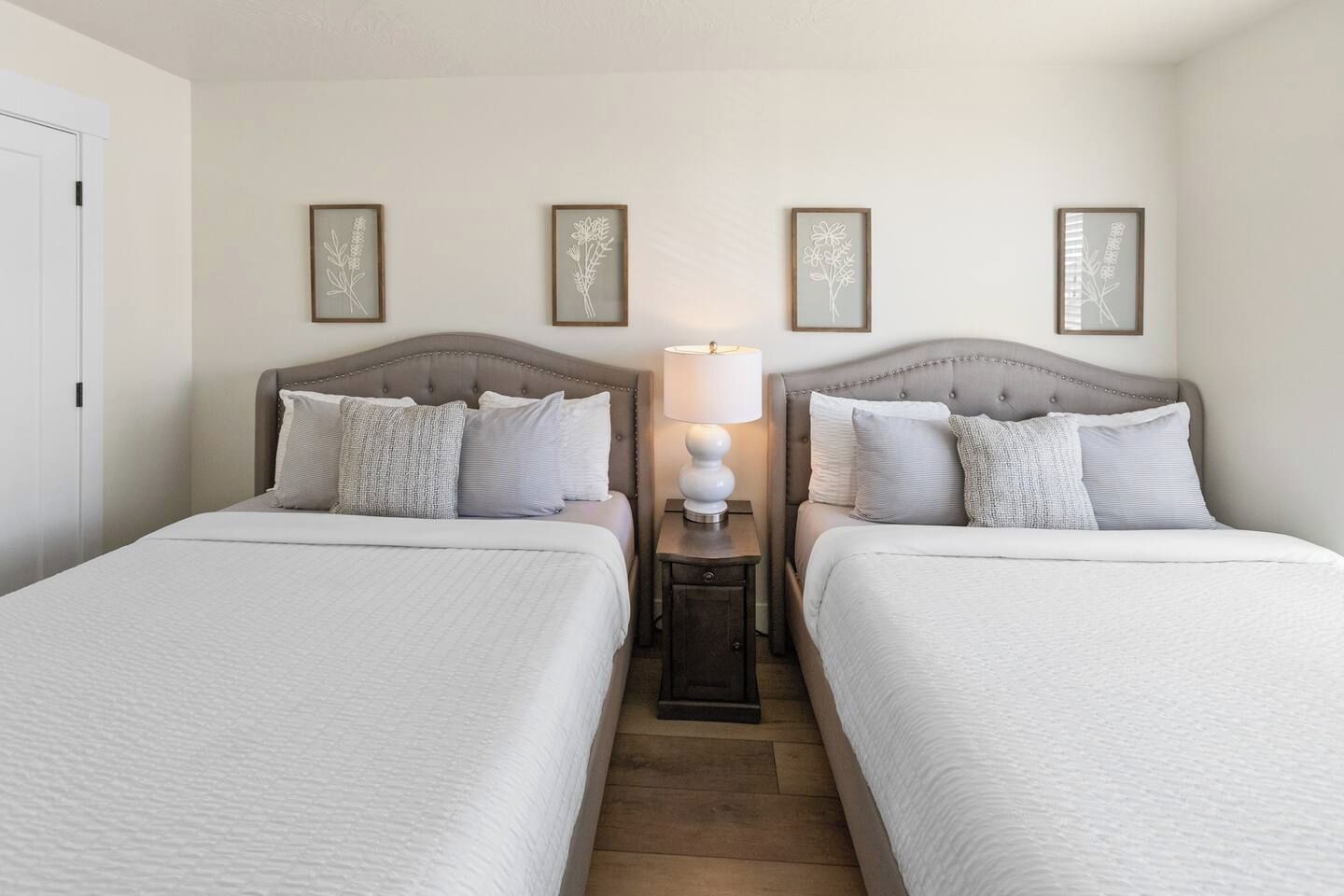 Habitación de hotel con dos camas, una mesita de noche con lámpara y decoración en las paredes.