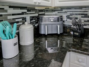 A kitchen with a granite countertop, a coffee maker, a set of knives, and a container with utensils. - Sous le Soleil- Canal, Heated Pool & Beach Gear! (Cape Coral)