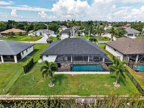 A residential area with houses, a swimming pool, and a well-maintained lawn. - Sous le Soleil- Canal, Heated Pool & Beach Gear! (Cape Coral)