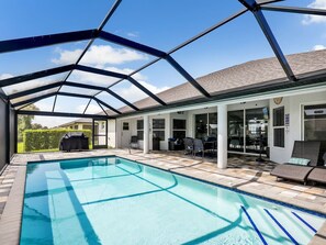 Ein überdachter Pool mit einer Terrassenfläche, Gartenmöbeln und Blick auf den Hinterhof.
