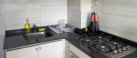 A kitchen with a black countertop, stainless steel appliances, and light-colored cabinets.