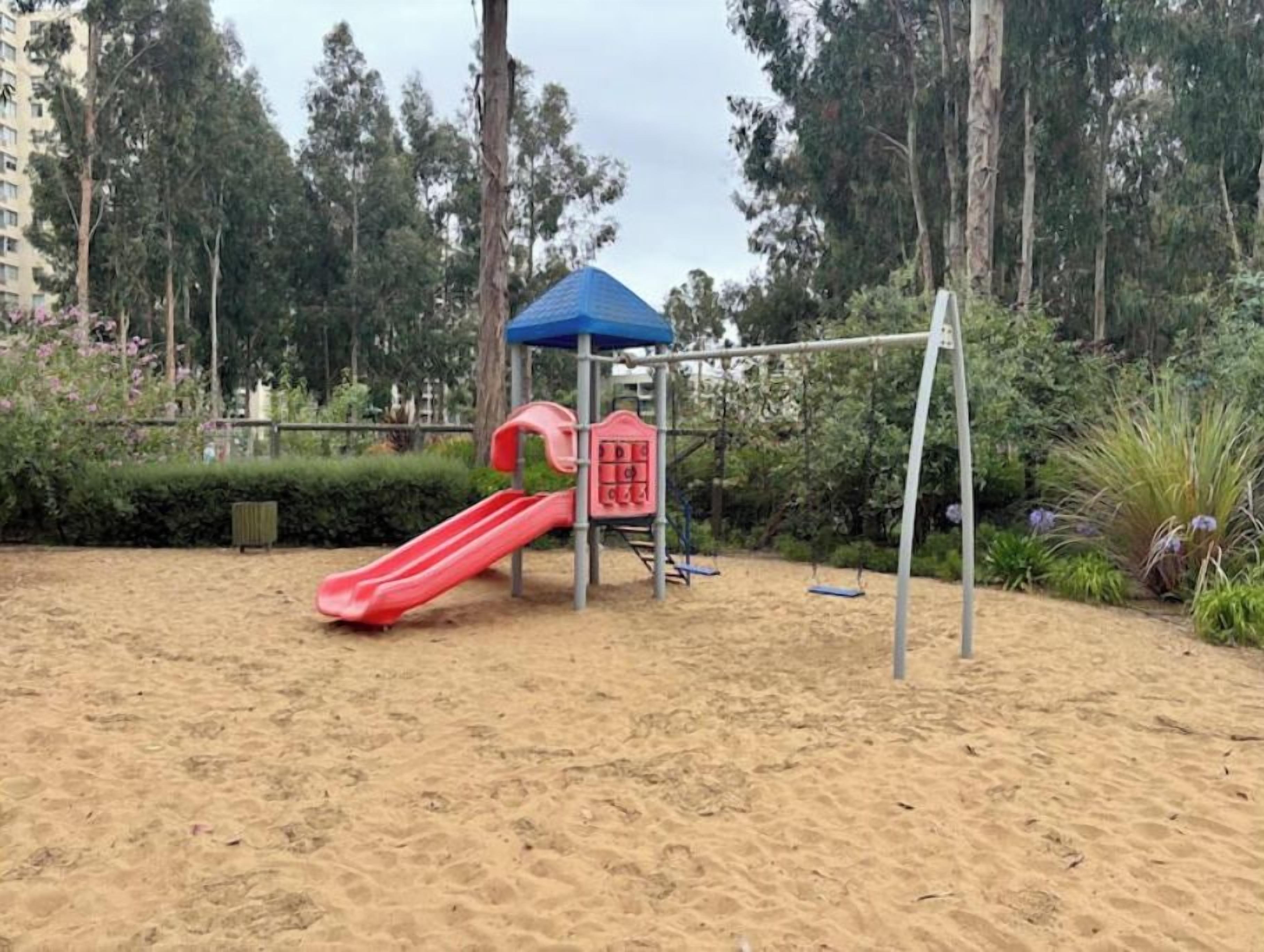 Ein Spielplatz mit einer roten Rutsche und einer Spielanlage mit blauem Dach.