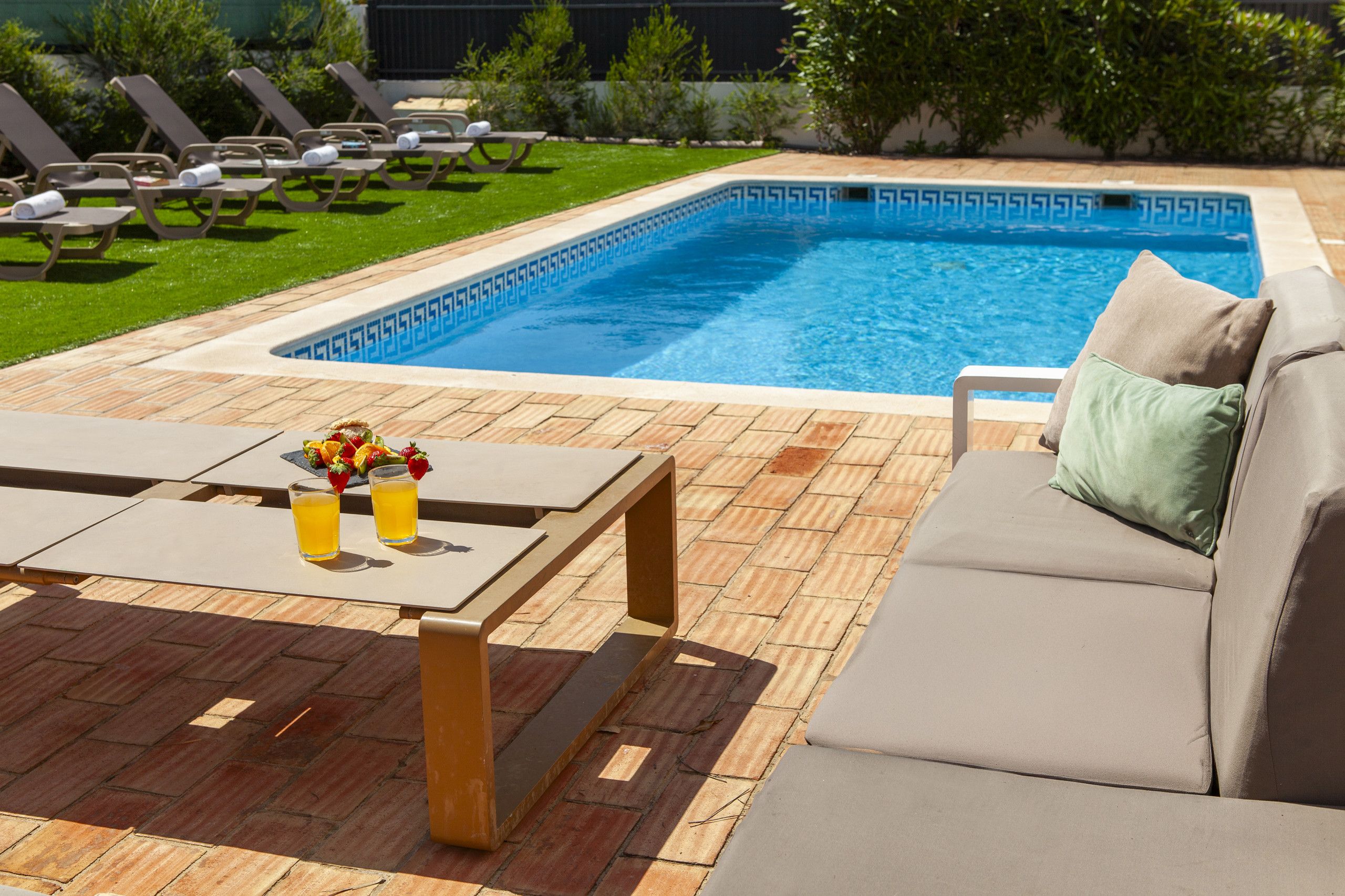 A swimming pool with lounge chairs and a table with drinks.