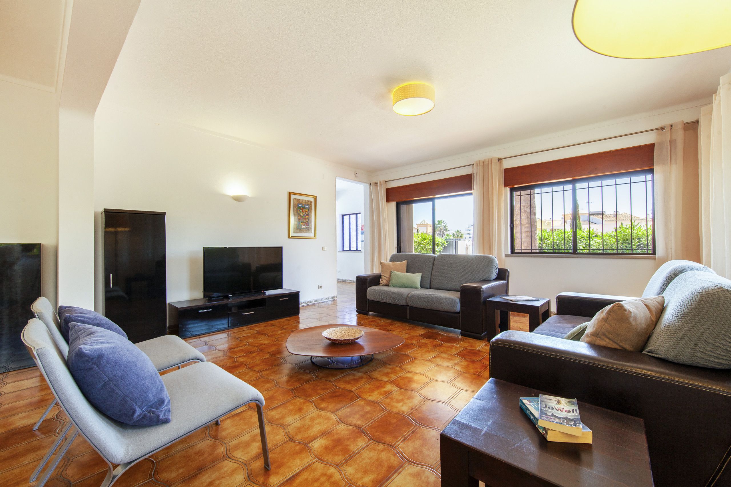 A living room with a sofa, armchairs, a coffee table, and a television.