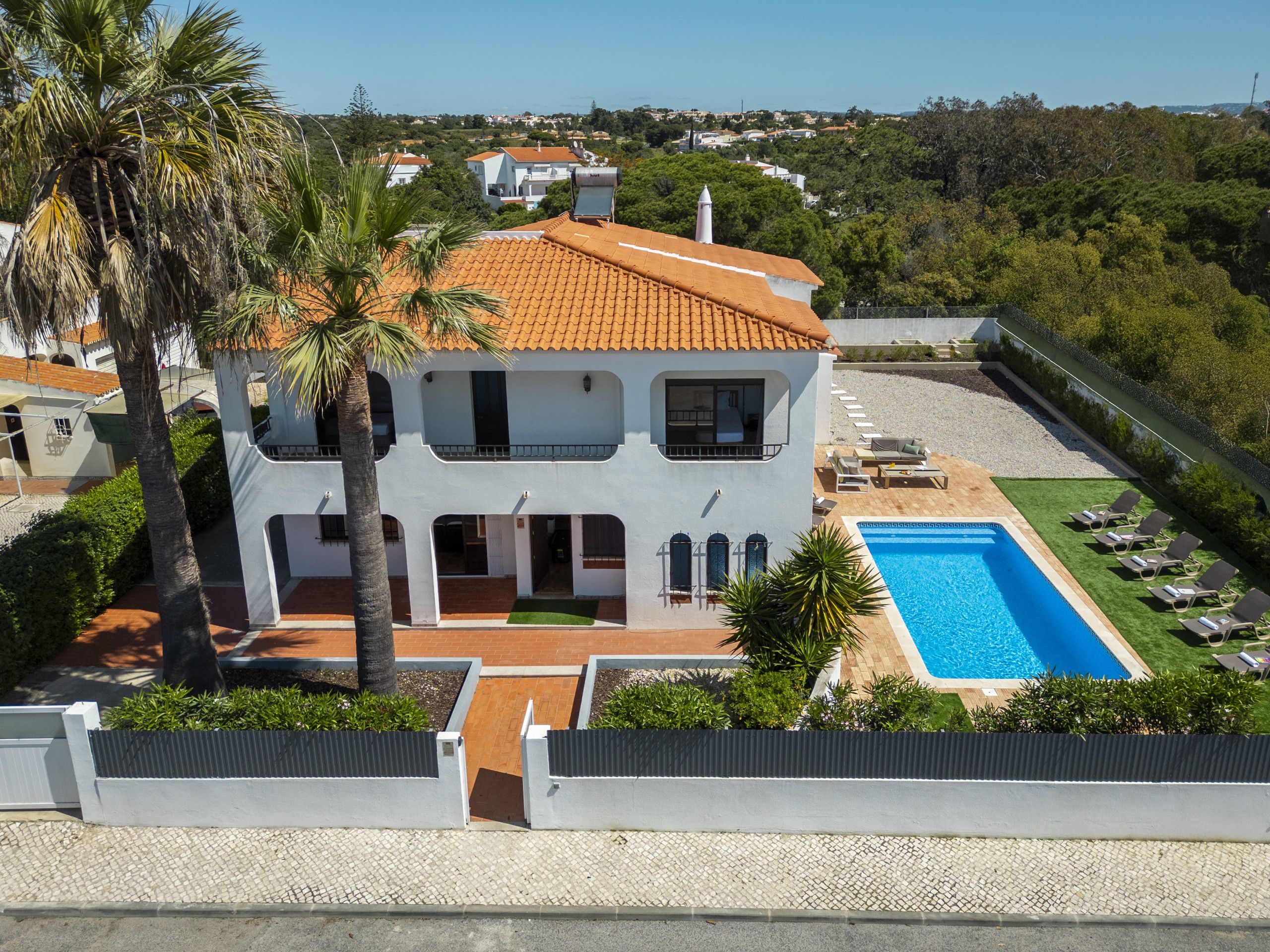 A two-story house with a swimming pool and sun loungers.