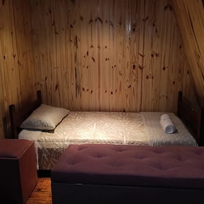 Un lit simple avec une couvre-lit à motifs dans une pièce aux murs en bois.