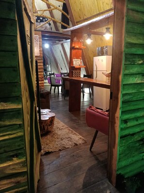 Un intérieur chaleureux avec un plafond en bois, un coin repas avec des chaises et une table, et un réfrigérateur.