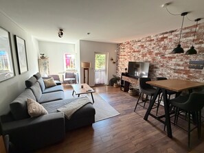 Un salon comprenant un canapé, une table basse et un meuble pour la télévision, sur lequel est posée une télévision à écran plat.