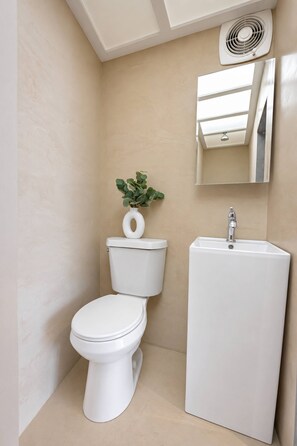 A modern bathroom with a toilet, sink, and a mirror above the sink. - Cozy Studio Steps from La Cerra (San Juan)