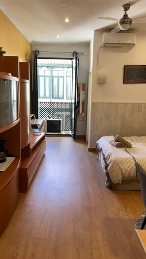 Ein Hotelzimmer mit einem Bett, einem Schreibtisch mit Stuhl, einem Fernseher und einem Balkon mit Blick.