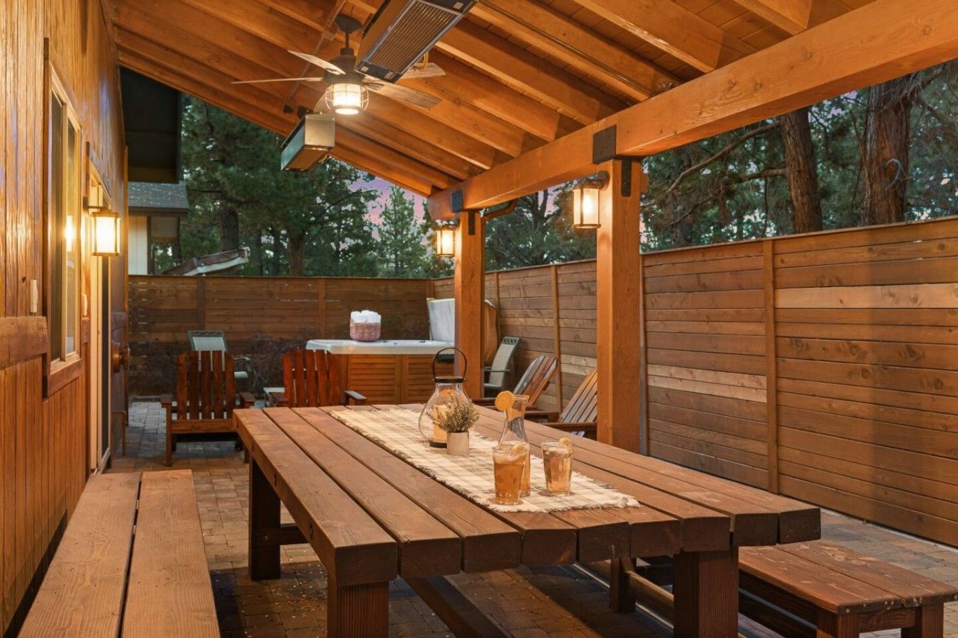 An outdoor wooden deck with a picnic table, chairs, and a barbecue area.