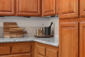 A kitchen with wooden cabinets, a granite countertop, and a cutting board. - Pine Lodge Chalet - Games Rm, Hot Tub, Dogs OK (Big Bear)